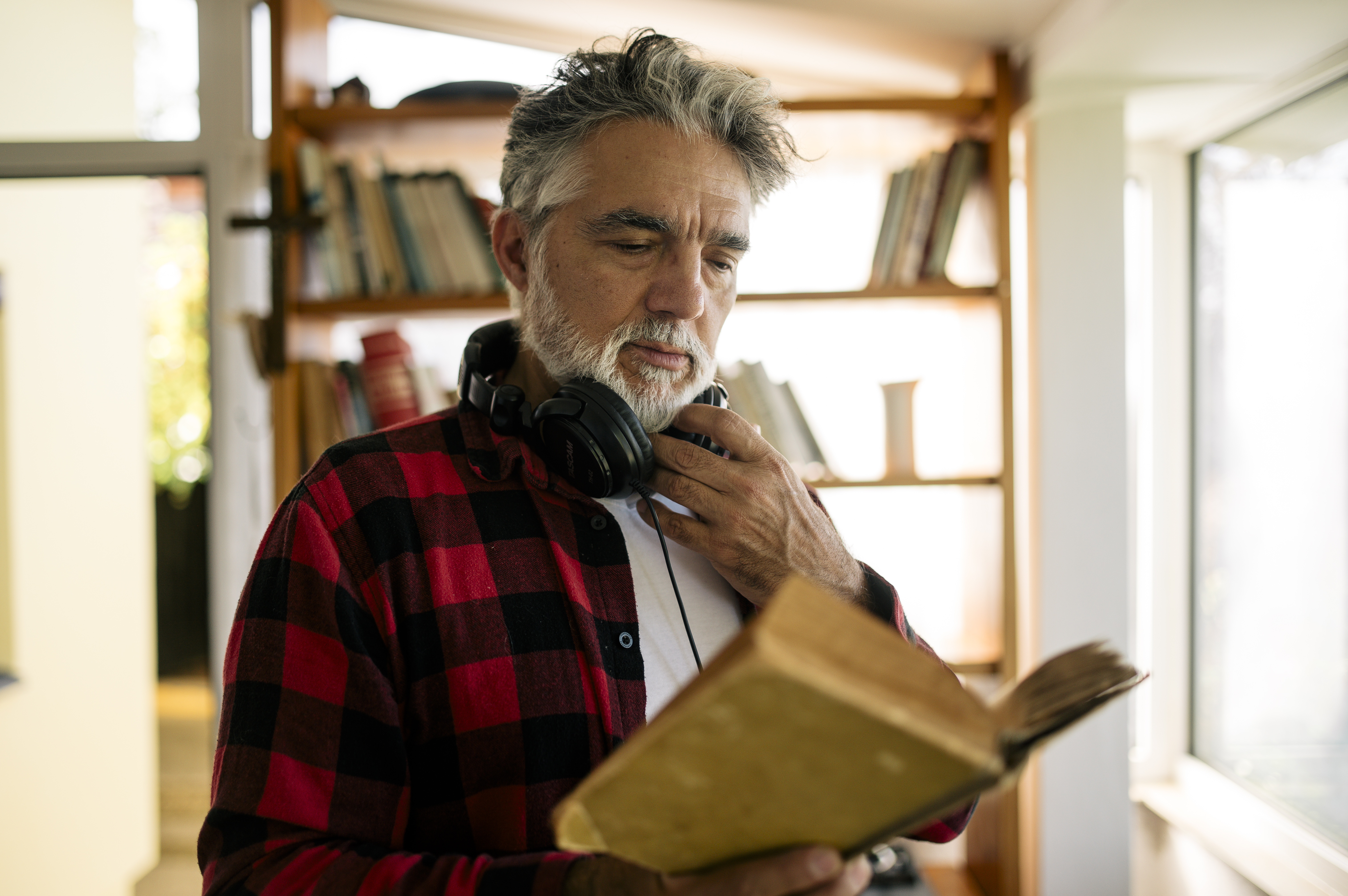 Reader wearing headphones with bookshelves in a warm room